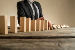 domino effect showing man tipping dominos on table